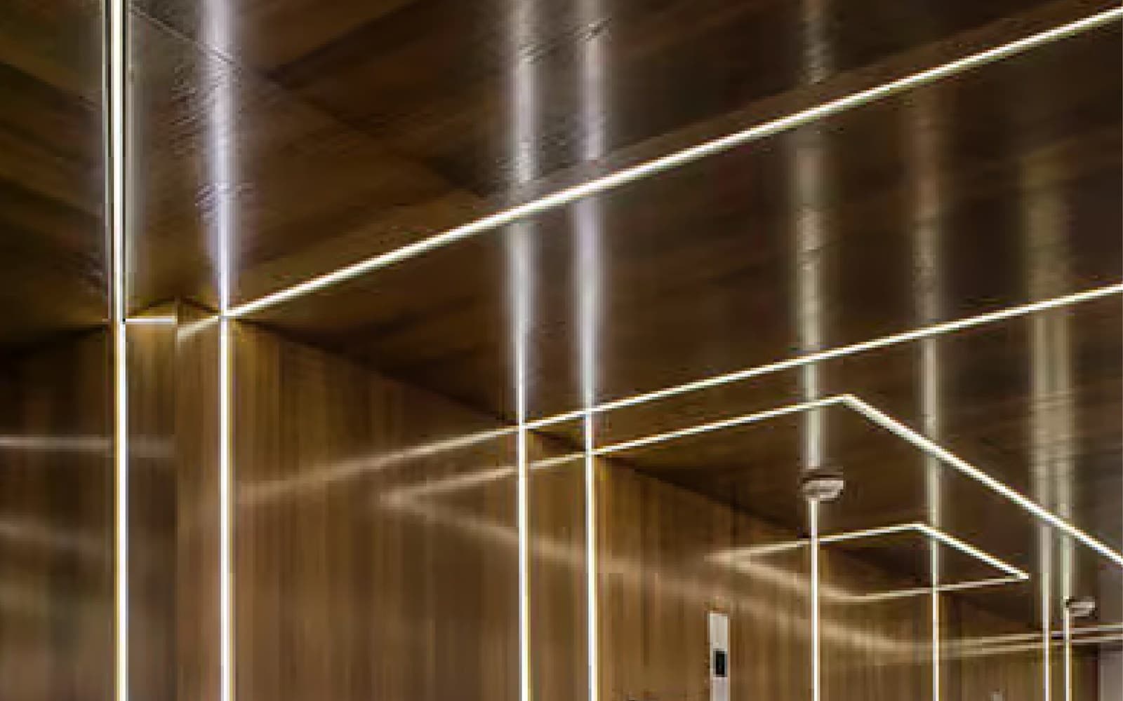 Linear aluminum groove lighting integrated into wood wall and ceiling surfaces.
